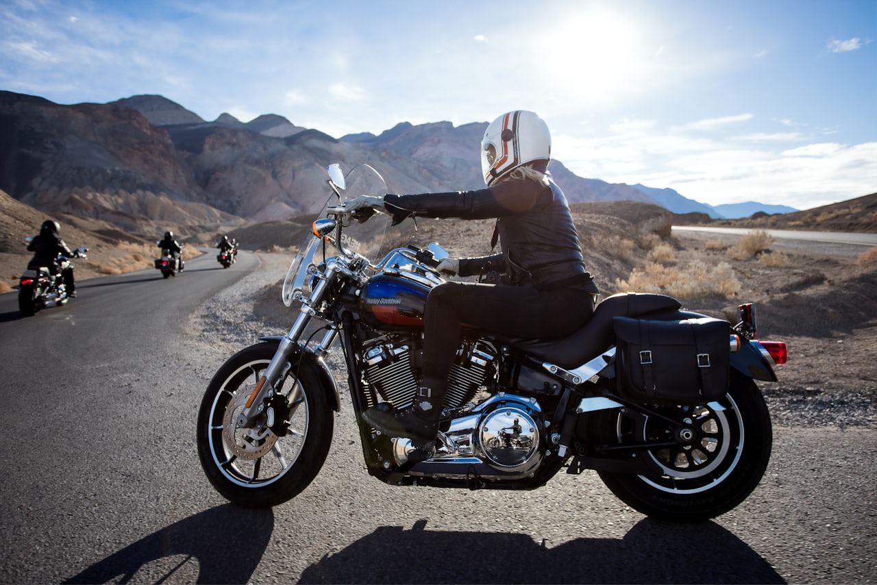 A full-fairing sport-touring motorcycle with an upright windscreen leans into a fast corner on an open mountain road, rider tucked in full gear, green-tinted bodywork catching late afternoon light.